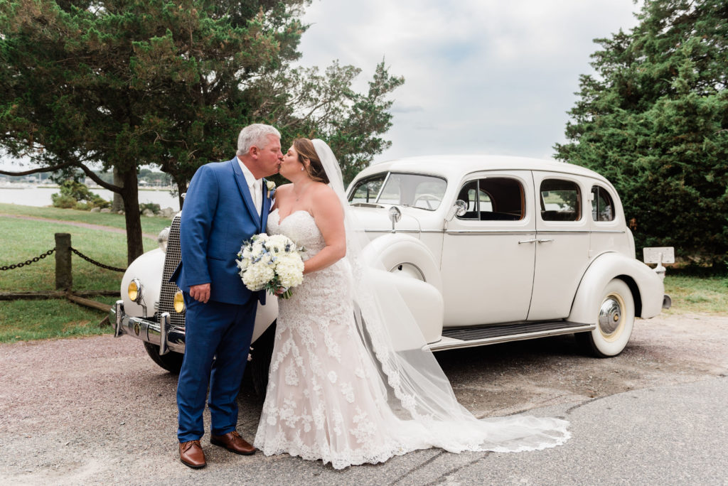 bride and groom kissing in front of car at Duxbury Bay