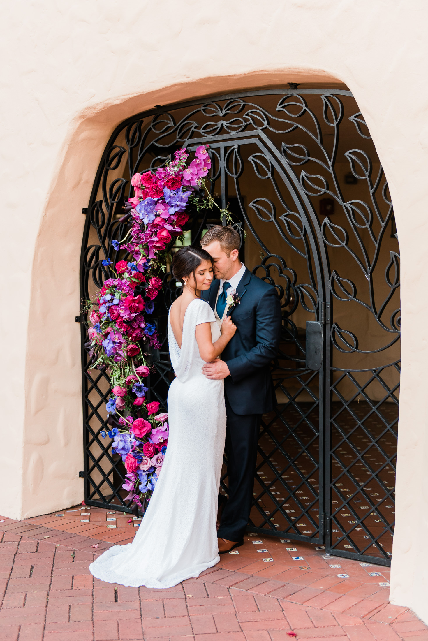 A wedding portrait of a couple under an elaborate floral installation at Curtiss Mansion in Miami Springs, florida