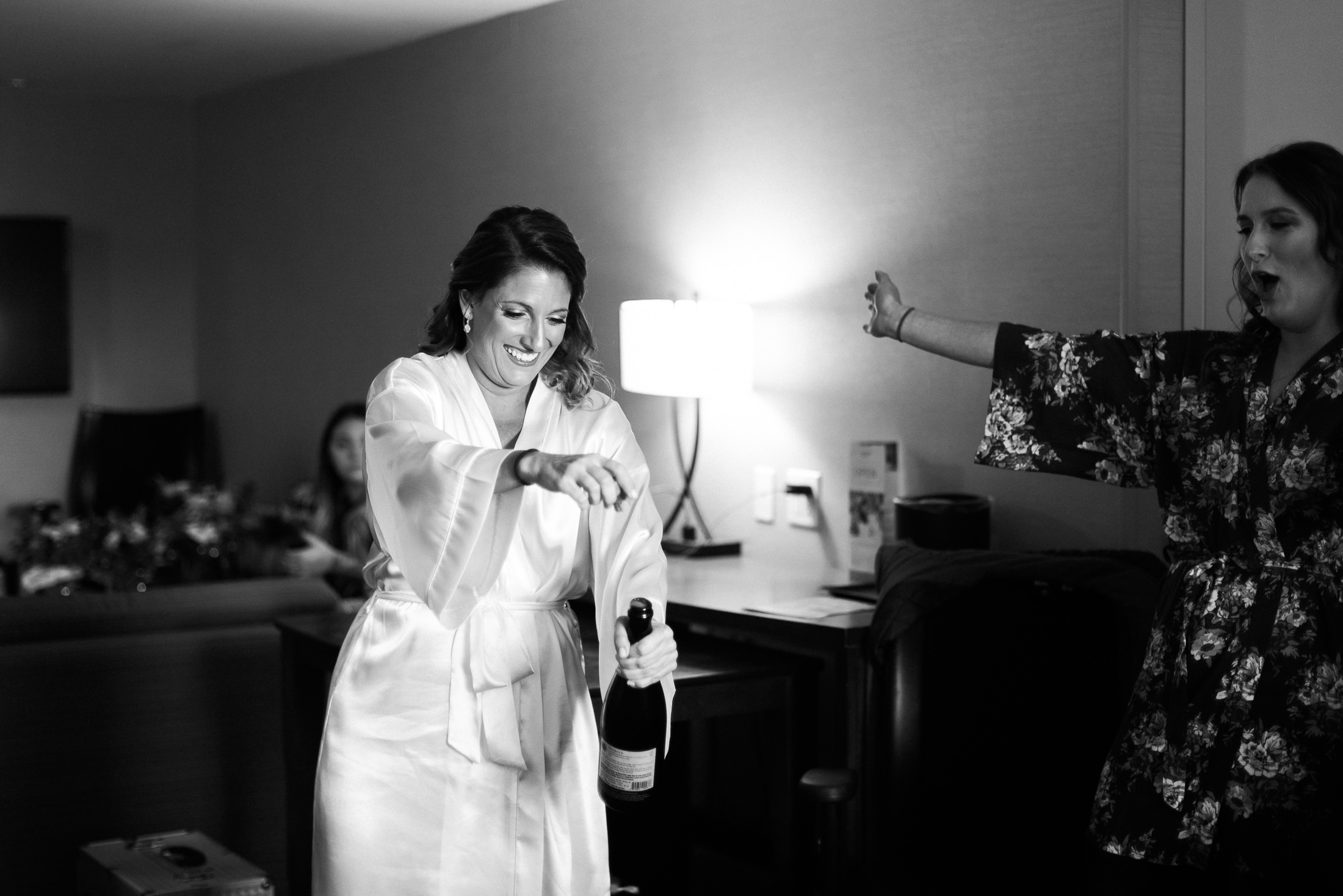 Bride popping champagne in bridal suite